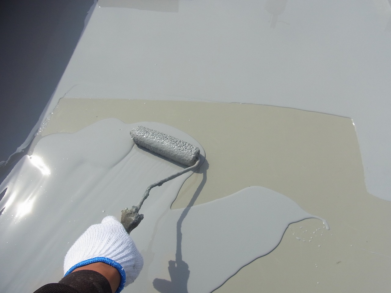 ベランダの床にローラーで防水材を塗る作業のイメージ
